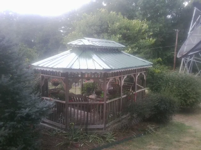 Green metal roof on a backyard gazebo surrounded by garden beds in Rockville