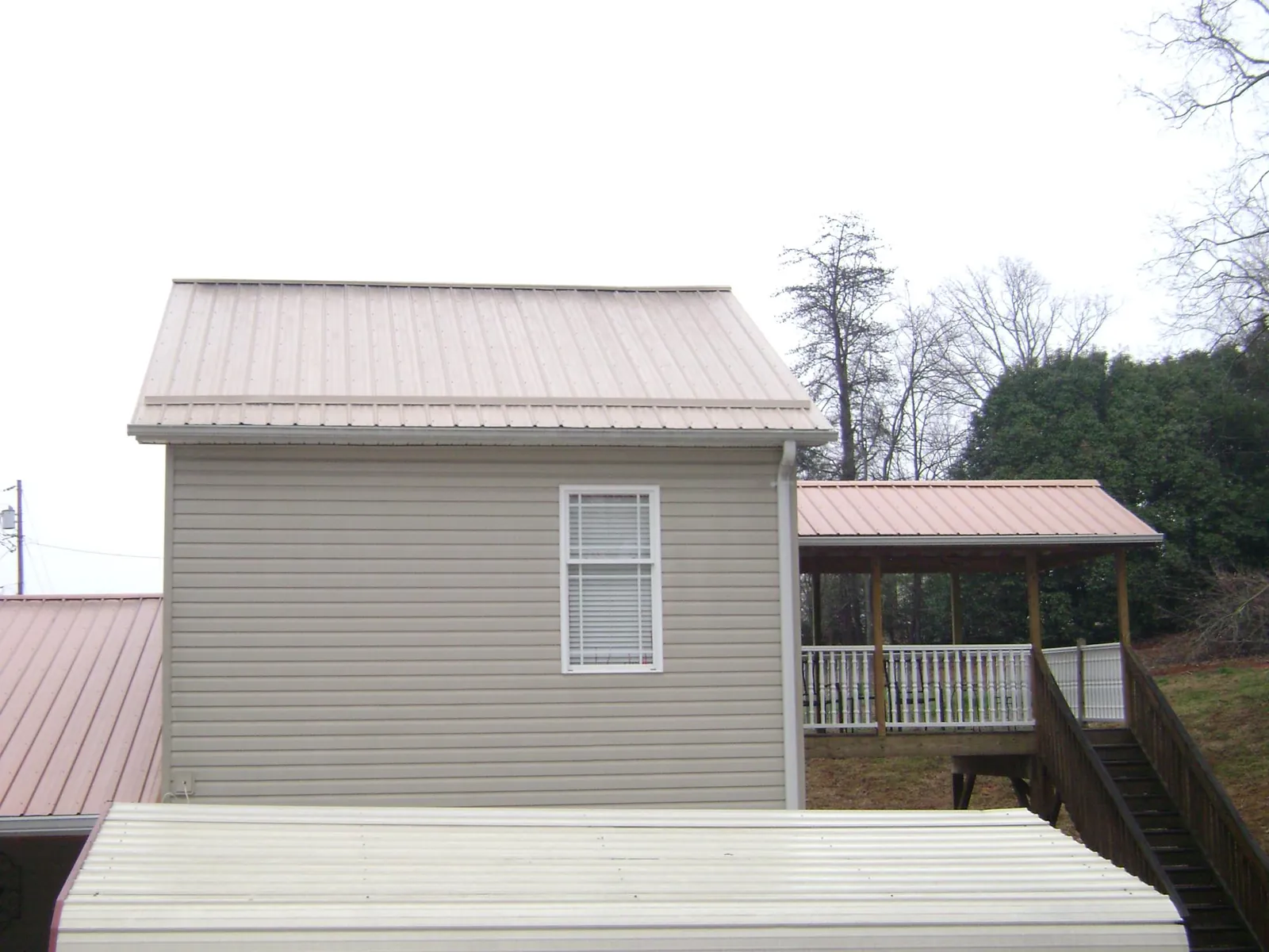 Tan metal roofs on a two story addition and attached porch, from a Roof Replacement job in Rockville